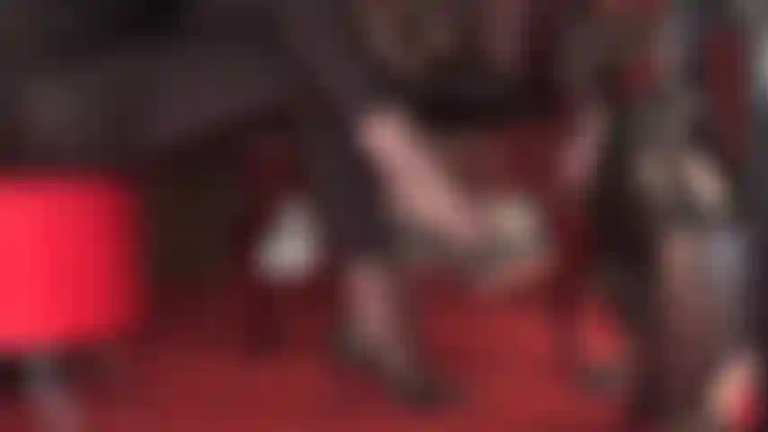 Indulge in this side view of black leather pumps dangling in pantyhose and shiny spandex leggings.