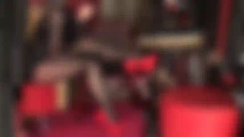 Leg tease in black layered shiny pantyhose, leather and red stiletto pumps. Crossed legs, black lipstick, hot red heels.