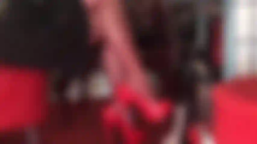 Seductive crossed legs in red pantyhose and glossy red pumps tease the aching slave cock.