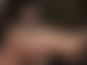 Mistress uses her lubricated shiny bare feet to stroke a black dildo.