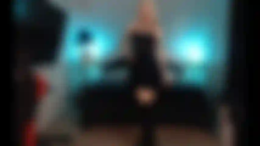 Cumming, wearing black dress and boots